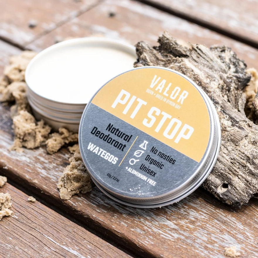 Valor Pit Stop Natural Deodorant tin in Wategos with amber label, open beside driftwood and sand