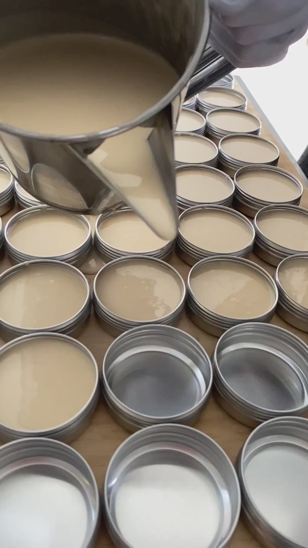 Hand-pouring Valor organic natural skincare balm into reusable aluminium tins during small-batch production