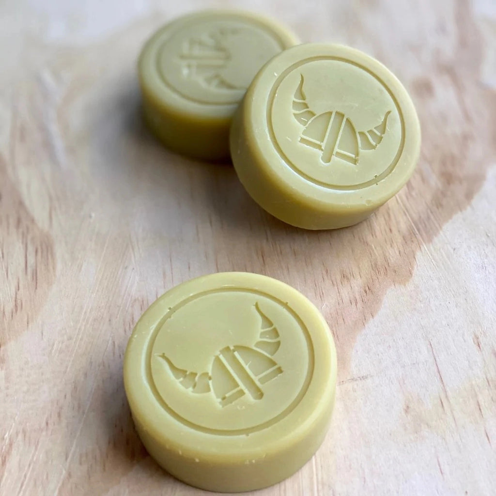 Three Valor shaving soap with embossed designs on a wooden surface