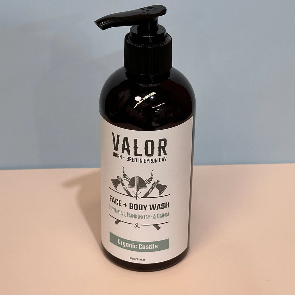 Bottle of Valor face and body wash on a beige surface with a light blue background
